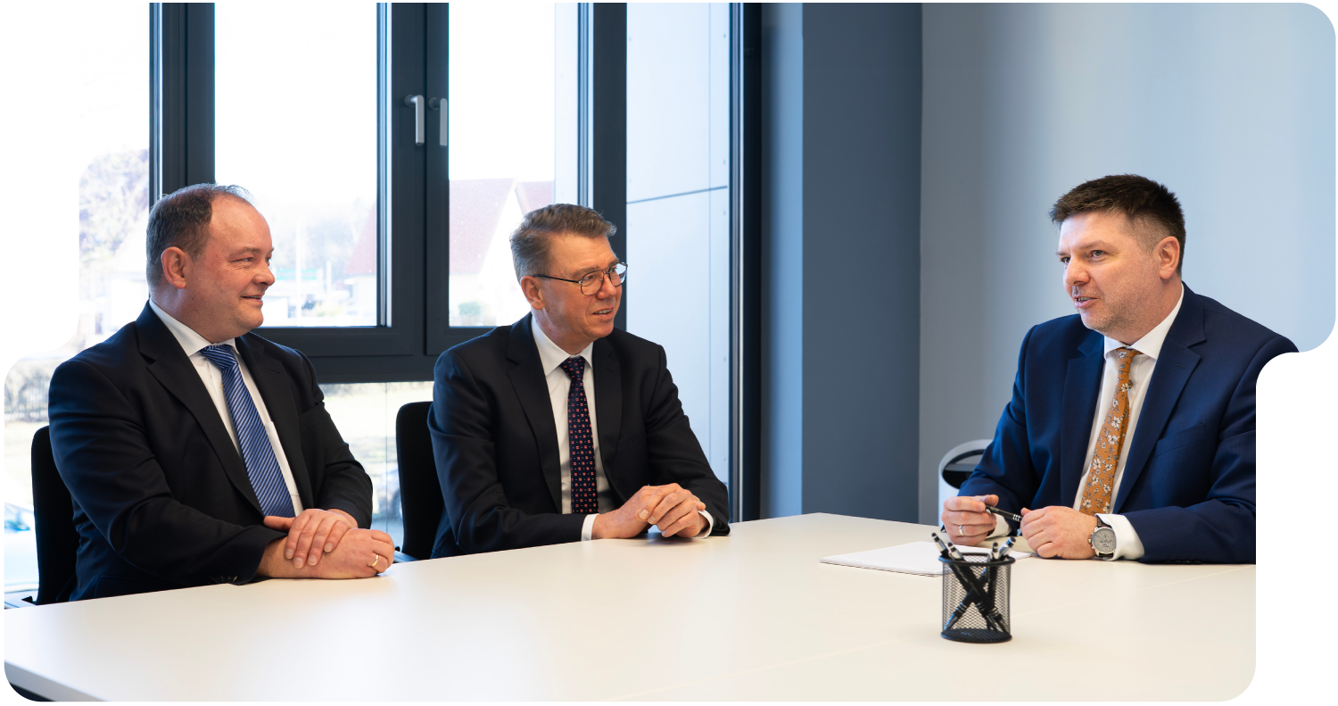 Drei Personen sitzen an einem Meeting-Tisch